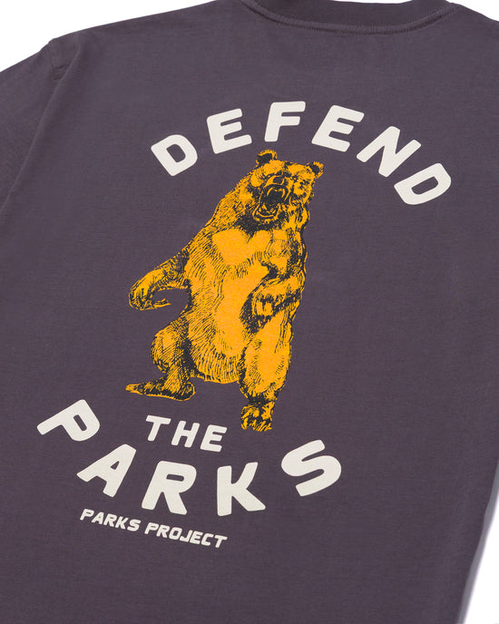 Close up of the purple Defend the Parks tee showing a yellow bear and the bold DEFEND THE PARKS text arching above and PARKS PROJECT beneath