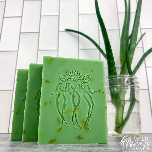 Bright green Desert Aloe Soap bars with an embossed emblem on a white tiled backdrop
