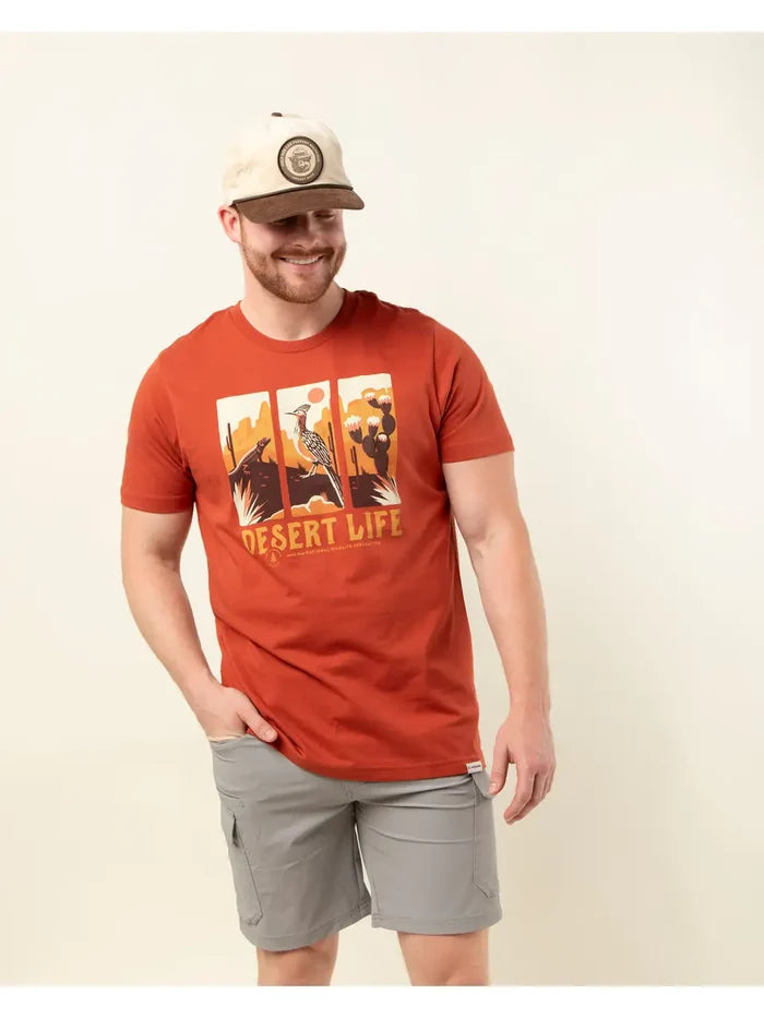 Man wearing red Desert Life T-shirt with desert scene graphic and light gray shorts.