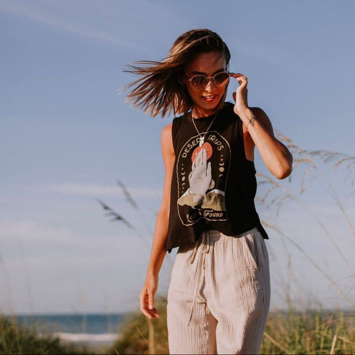 Woman in black Desert Trips Crop Tank outdoors with windblown hair and sunglasses