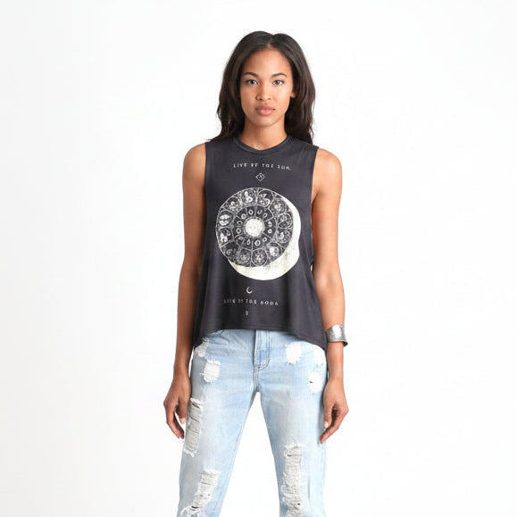 Full body shot of a model wearing the Eclipse sleeveless top with circular celestial print and distressed jeans.