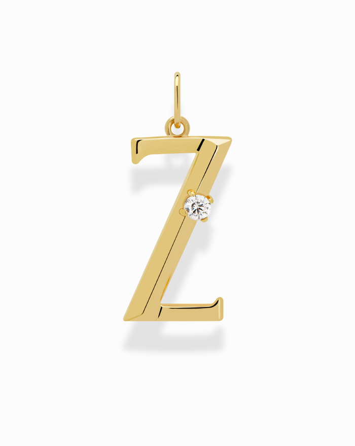 The Eloise Letter Charm by Mod + Jo is a gold pendant shaped like the letter Z, featuring a small round cubic zirconia on one side, shown against a white background.