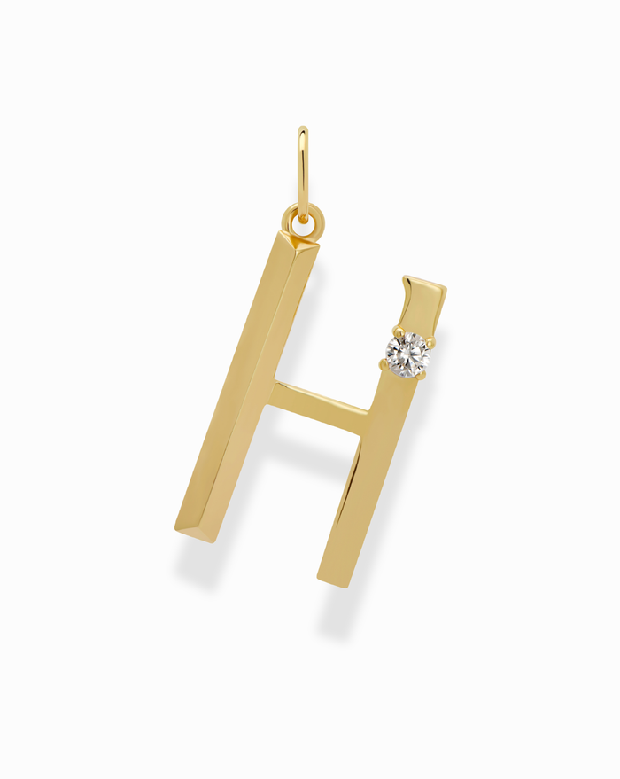 The Eloise Letter Charm by Mod + Jo features a gold-plated H-shaped pendant with a small round diamond accent on the upper right, shown on a white background—a stunning initial accessory.