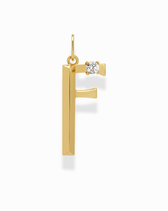 The Eloise Letter Charm by Mod + Jo features a gold F-shaped pendant with a small round diamond at the top right, ideal for a personalized necklace. Shown on a white background.
