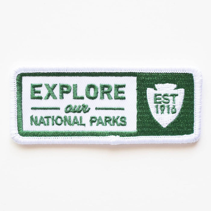 Rectangular embroidered patch with green border and white center displaying Explore Our National Parks and a shield emblem.