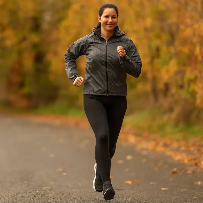 Woman running on a path whilst wearing a pair of Sub Zero Factor 1 Plus stretch leggings with autumn foliage in the background