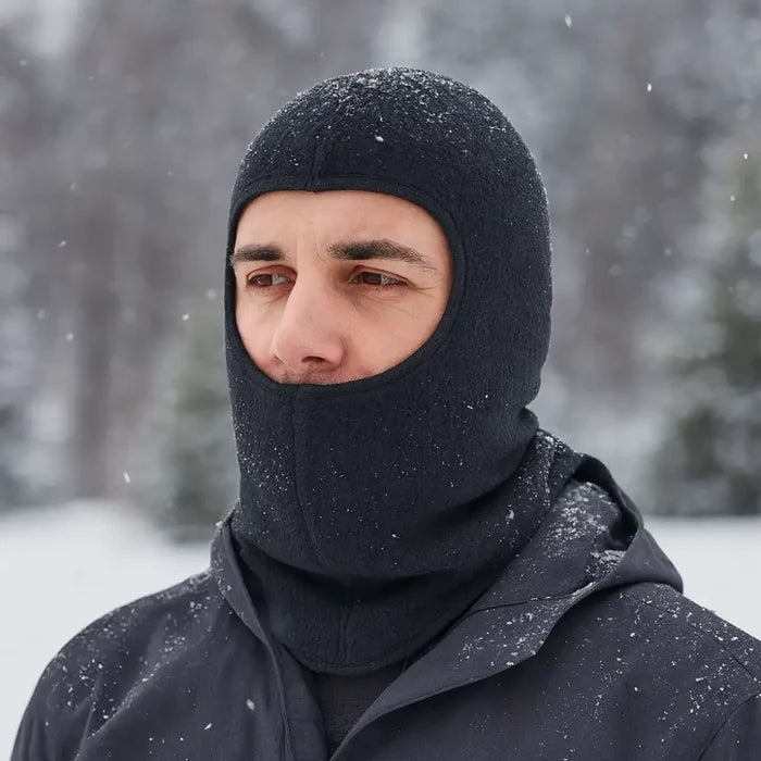 Head and shoulders shot of a man wearing a Sub Zero Factor 3 polyester balaclava in black outdoors in a winter scene
