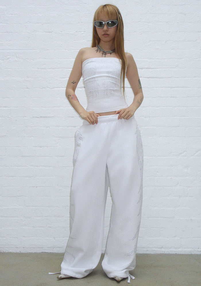 Model wearing a white tube top with rhinestones and loose white sweatpants in a front view.