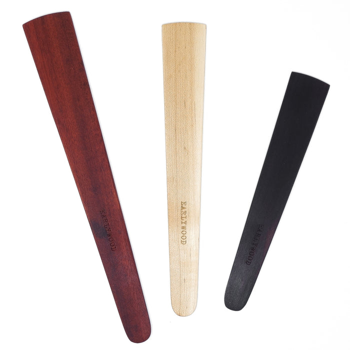 Flat Saute Set three wooden spatulas burgundy natural and black arranged upright on white background.