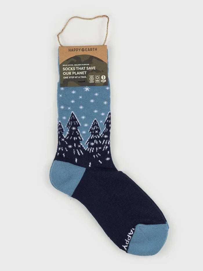 Forest Flurries socks in blue with white snowflakes and dark pine trees, attached to a brown tag.