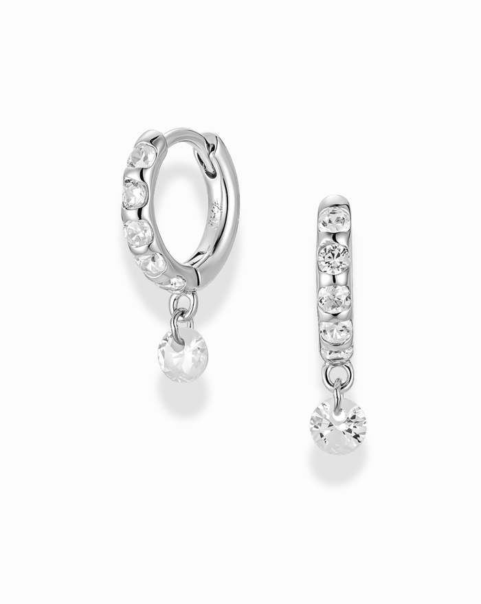Silver hoop earrings with clear gemstones channel set in the hoop with a floating cz drop on a white background