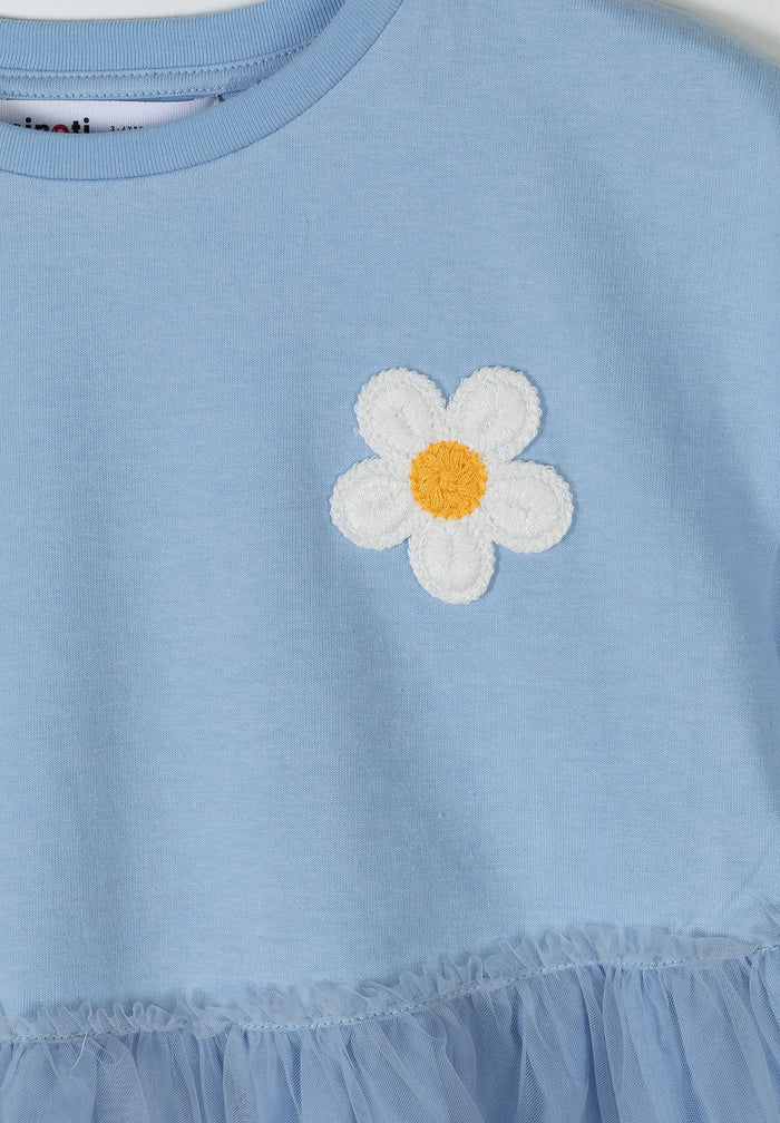 Close-up of a blue jersey dress with a crochet flower embellishment.