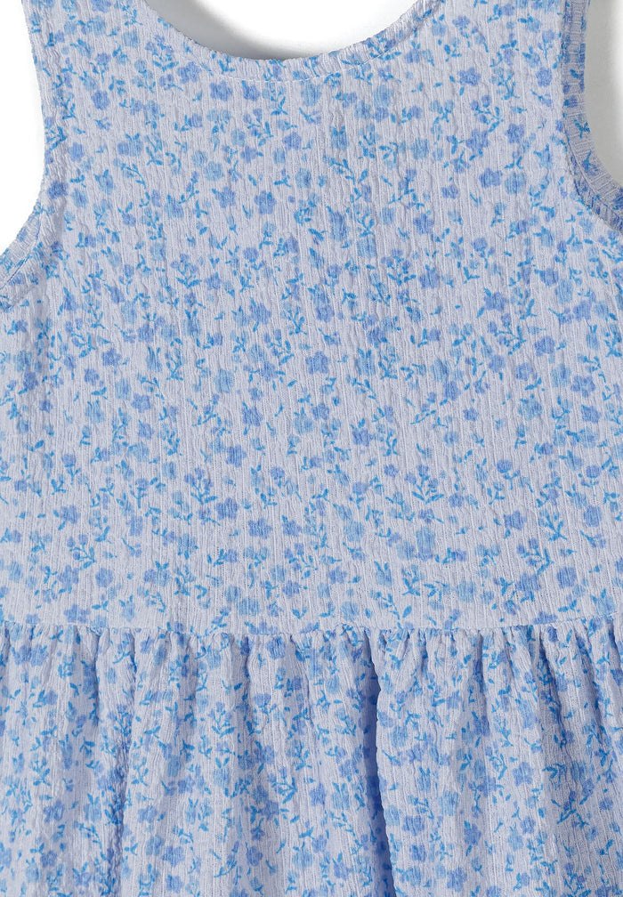 Detail of a girls' sleeveless blue floral summer dress with tiered design.