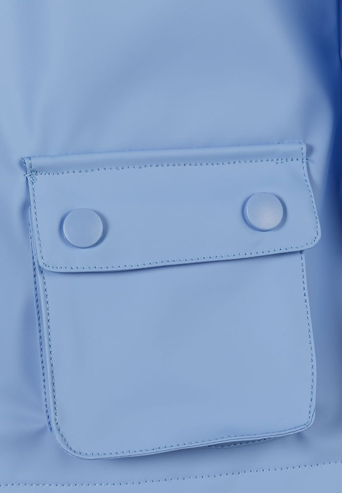 Detail of a blue waterproof rain jacket with a flap pocket and snap buttons.