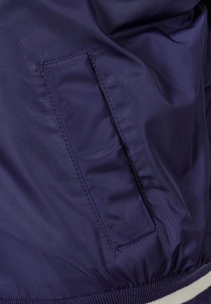 Detail of navy varsity bomber jacket showing side-seam pocket and elasticated cuff.