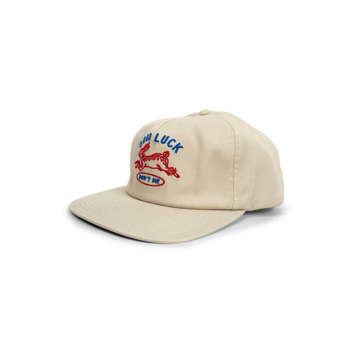 Beige cap shown in a three-quarter view with blue Good Luck text and red running dog embroidery and Don't Die inside a blue oval