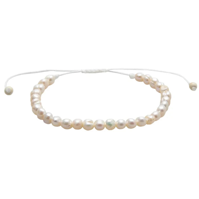 Freshwater pearl bracelet with creamy white beads and a small gold charm on an adjustable white cord