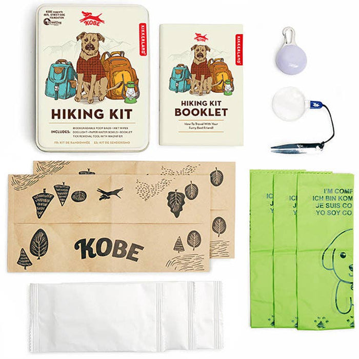Hiking Buddy Dog Kit contents laid out including illustrated metal tin, booklet, kraft envelopes, and assorted hiking accessories.