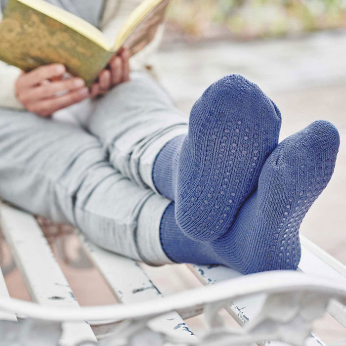 Lifestyle shot of HJ Hall non-slip feet warmer socks being worn by a person reading a book sitting on a bench