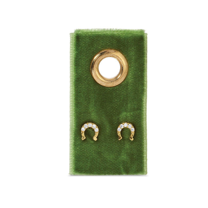 Diamond-studded gold horseshoe stud earrings on green velvet display