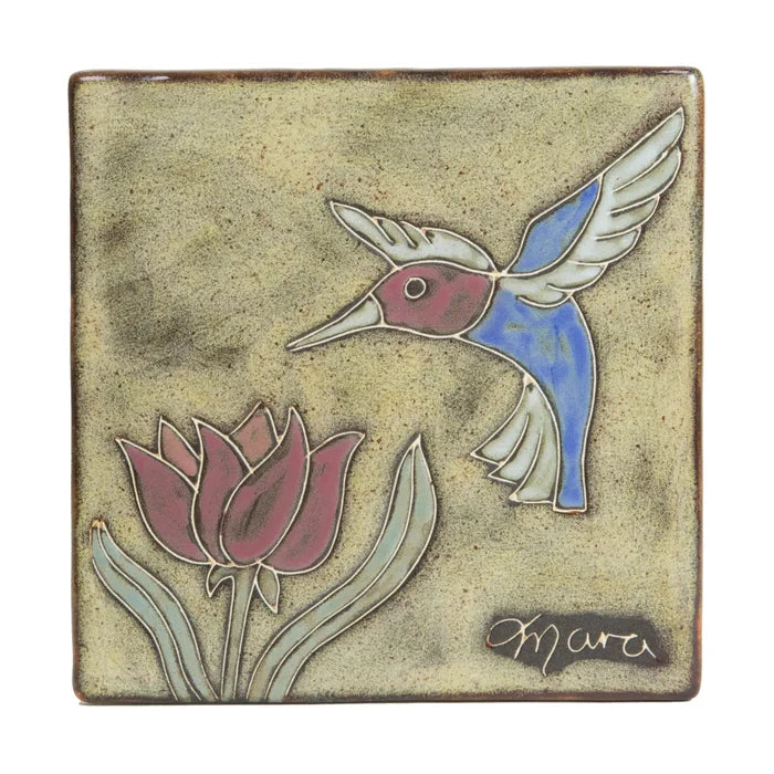 Six inch ceramic trivet featuring a blue and purple hummingbird and a flower on a beige speckled glaze