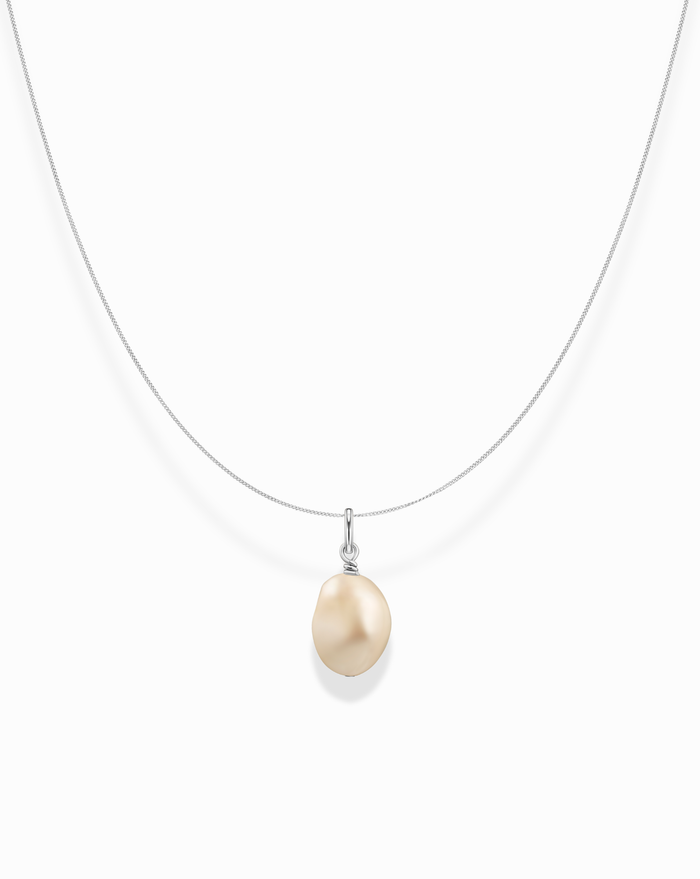 The Imogen Pendant Necklace features a delicate silver chain and a single, uniquely shaped light golden freshwater pearl, beautifully centered on a white background.