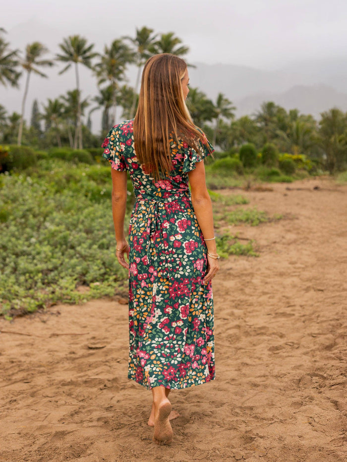 Isla Dress Wildflowers printed dress worn by a woman walking barefoot on a sandy path.