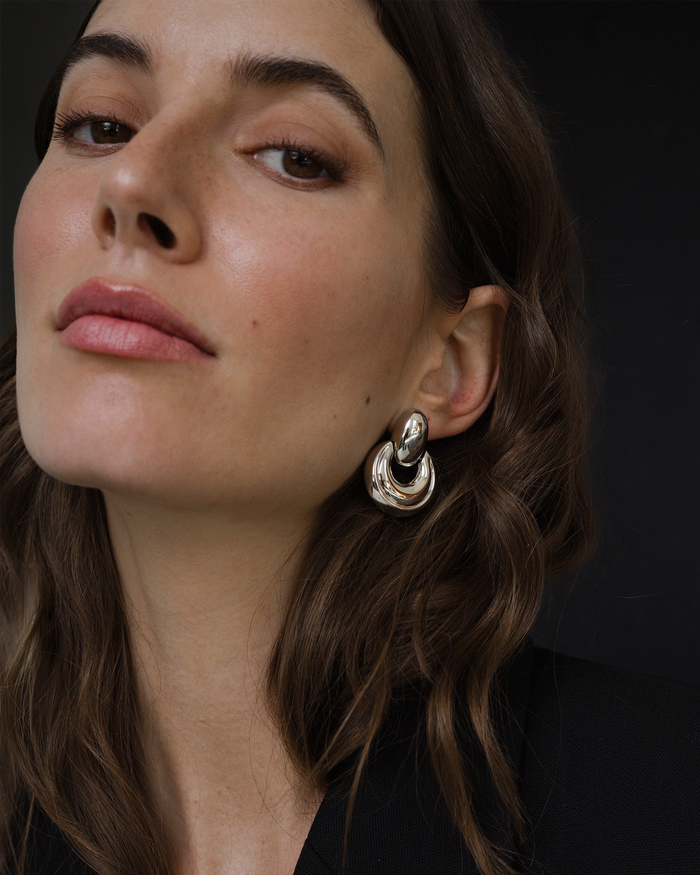 Close-up of a woman wearing a silver earring against a dark background