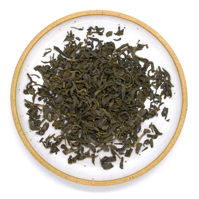Loose jasmine green tea leaves on a round white plate