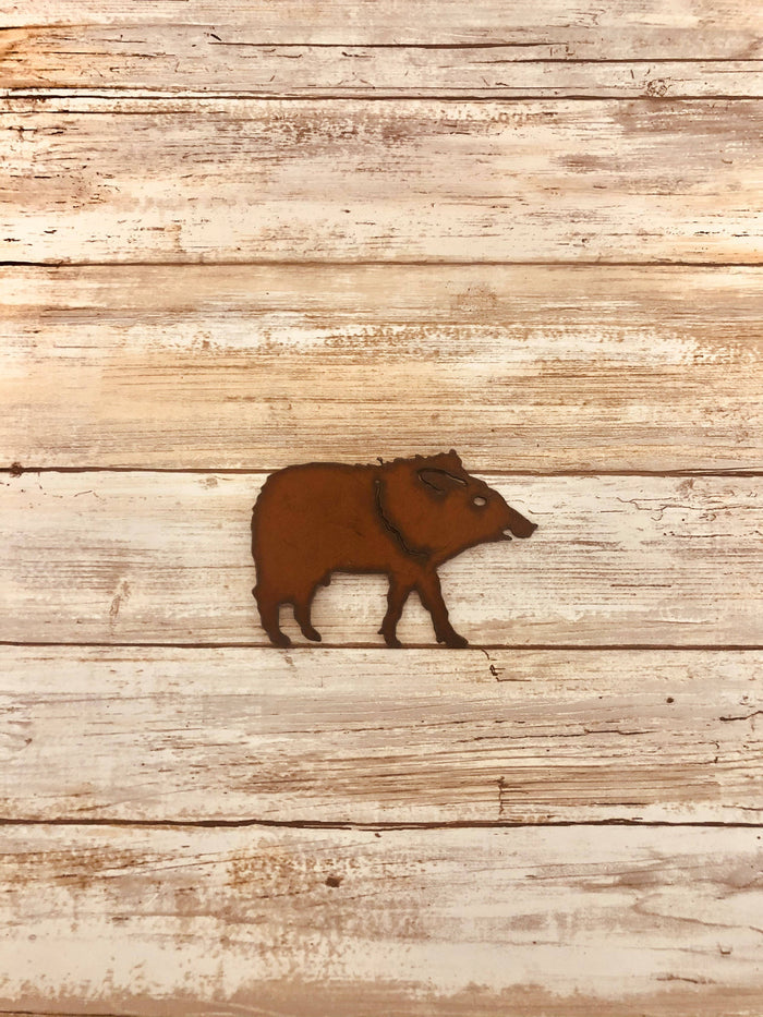 Rusty javelina magnet silhouette on a weathered wooden surface
