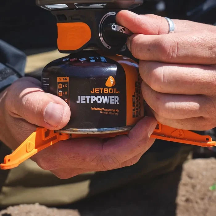 Lifestyle image of a man holding a Jetboil canister that has the stabiliser legs attached