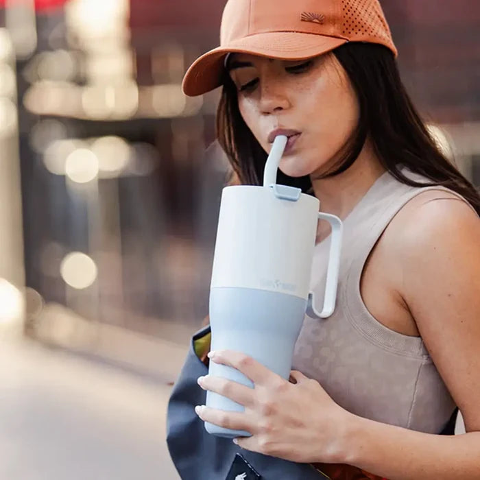 Lifestyle image showing a woman drinking through the straw of a Klean Kanteen 1046ml rise tumbler in ice blue colour
