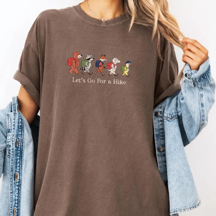 Embroidered brown tee featuring five hiking animals with backpacks and the Let s Go For a Hike slogan