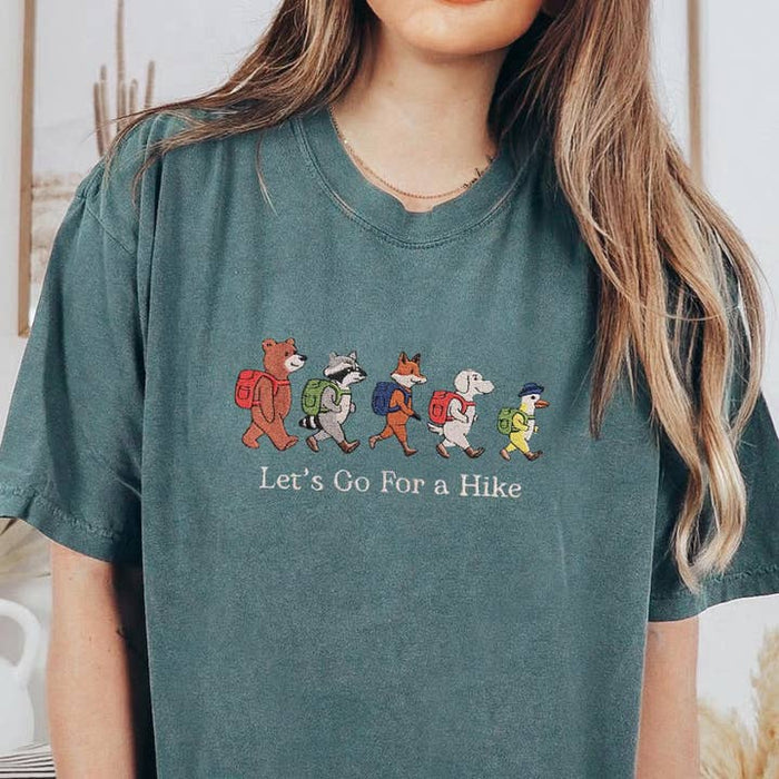 Teal embroidered tee showing hiking animals with backpacks and the caption Lets Go For a Hike