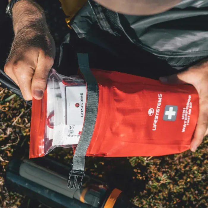 Somone removing the contents of a Lifesystems Mini Waterproof First Aid Kit when outdoors