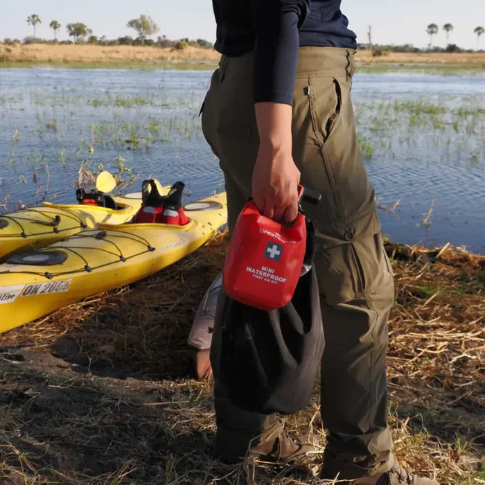 A person carrying a Lifesystems Mini Waterproof First Aid Kit after leaving their kayak