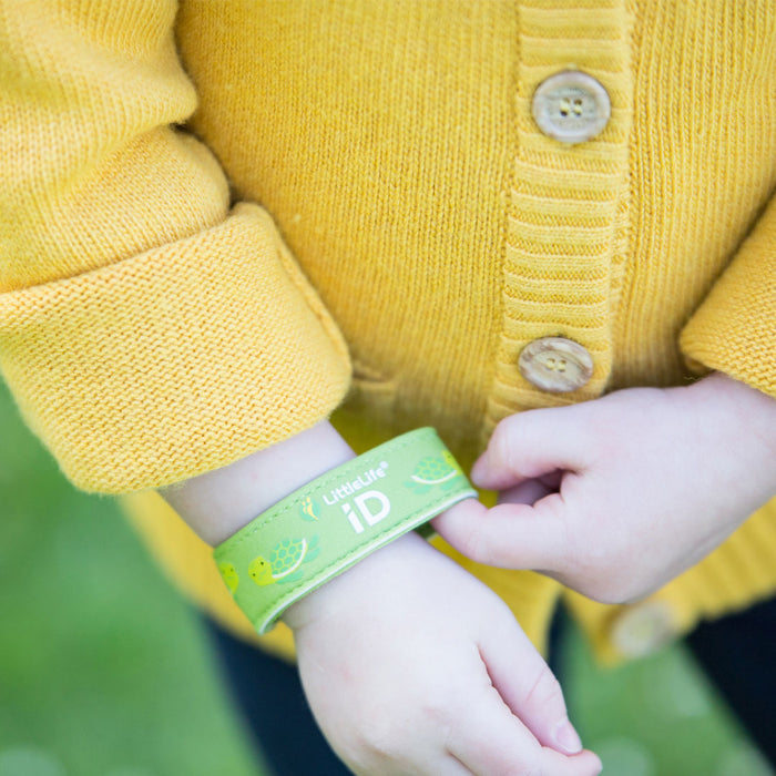 Lifestyle shot of a child putting on their Littlelife Turtle identification wristband