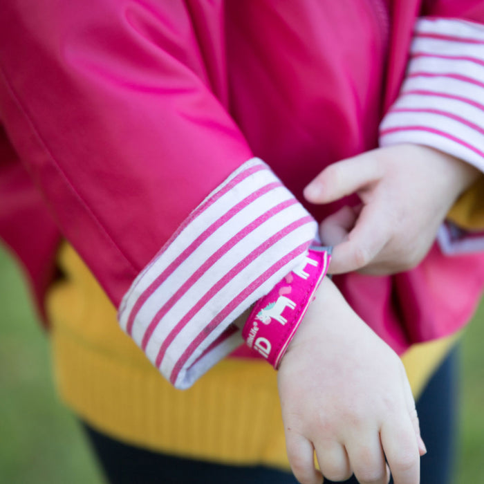 Lifestyle shot of a child putting on their Littlelife Unicorn identification wristband