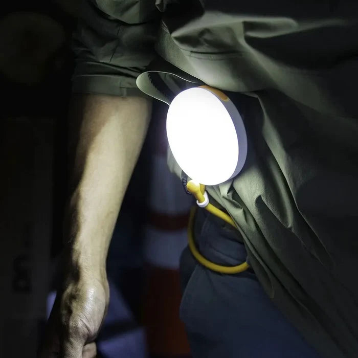 Lifestyle image of a person using a Luci portable solar powered light fixed around their waist in the dark to illuminate their surroundings