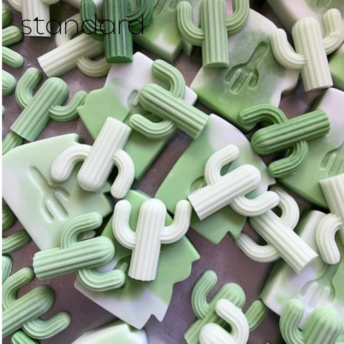 Assorted pale green cactus shaped soaps and curved pieces scattered on a surface.