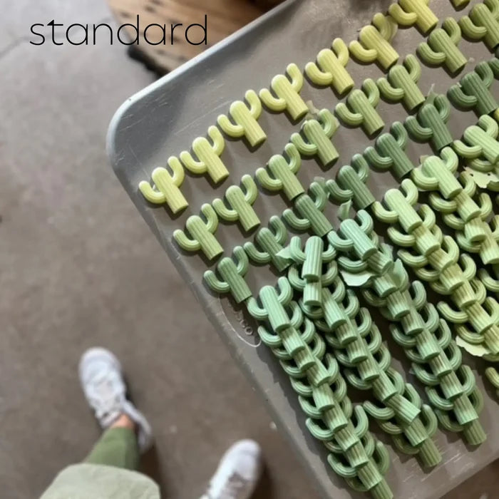 Rows of pale green cactus shaped soaps on a metal tray photographed from above