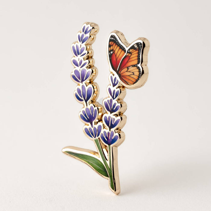 Gold edged enamel pin with a lavender sprig and an orange monarch butterfly