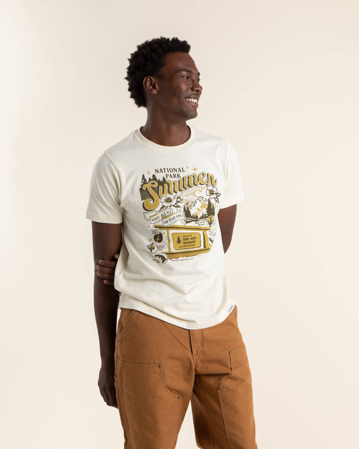 Side view of a man wearing a cream National Park Summer tee with a retro graphic.