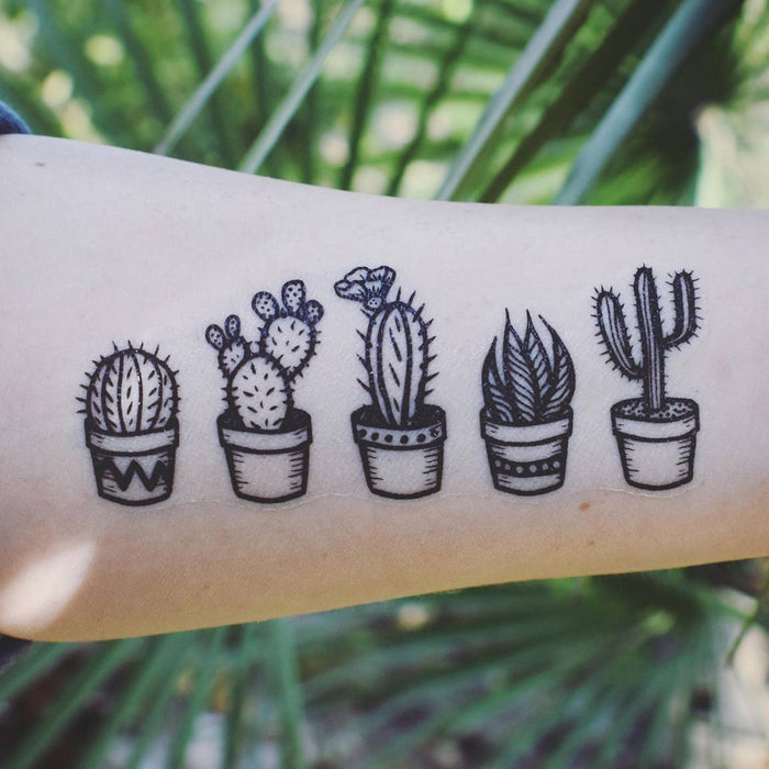 Forearm with black line drawings of potted cacti from a temporary tattoo sheet