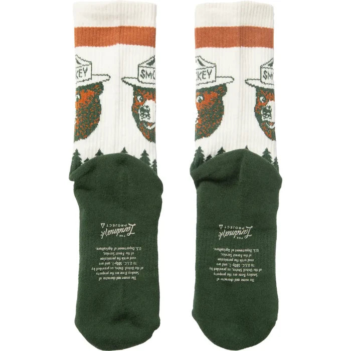Pair of Smokey Bear forest pattern socks with white tops and dark green feet
