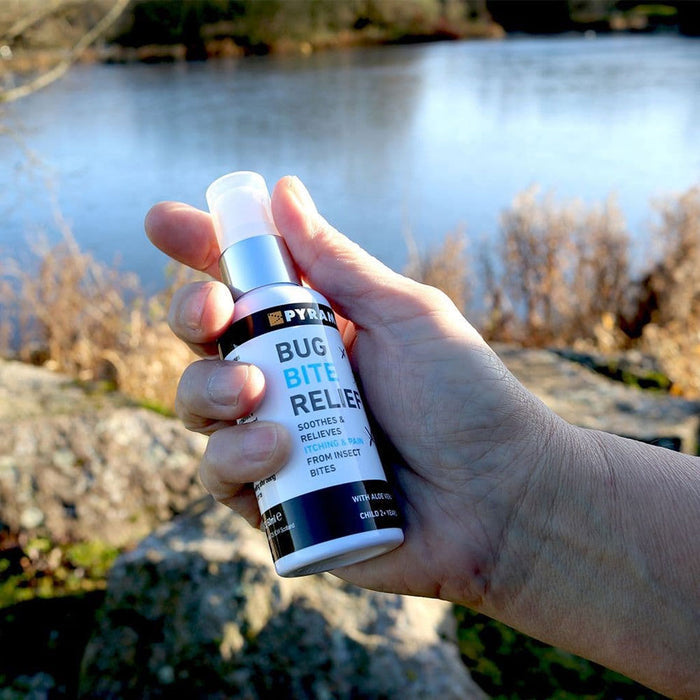 Pyramid insect bite and sting relief spray bottle held in someones hand outdoors
