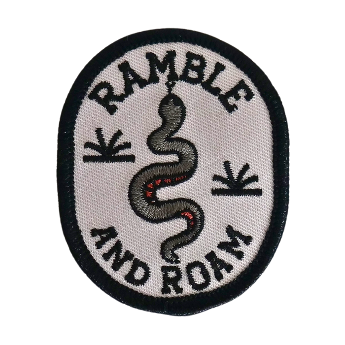 Round white patch with a black border and embroidered snake design and Ramble and Roam lettering