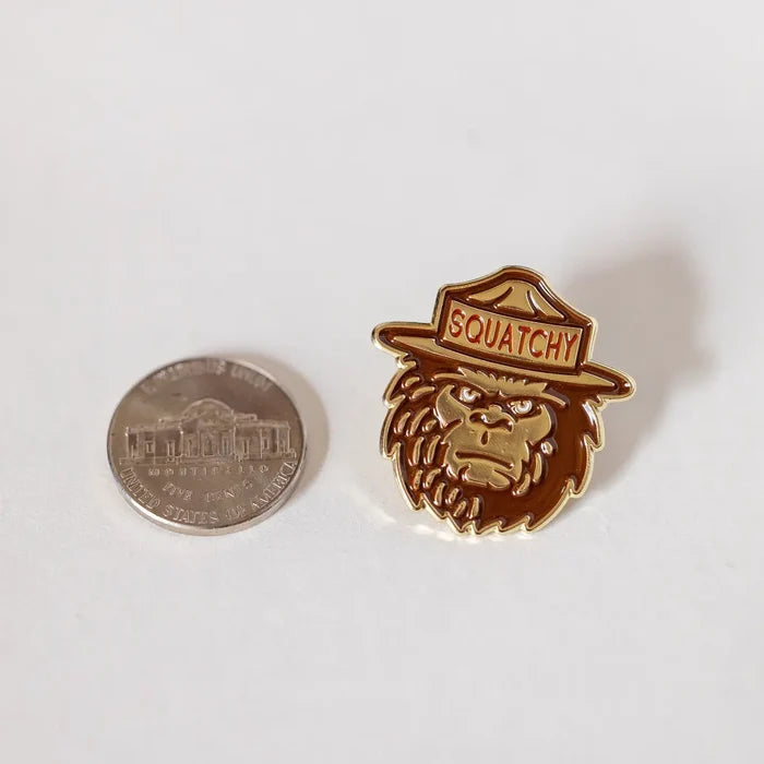 Ranger Squatchy enamel pin shown next to a US quarter for scale on a white background