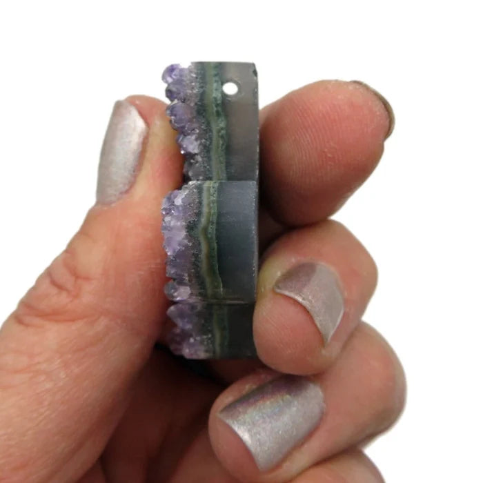 Close up of a purple amethyst cactus crystal pendant held between fingers
