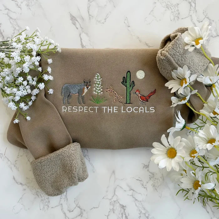 Beige embroidered sweatshirt with a desert scene and the text Respect The Locals